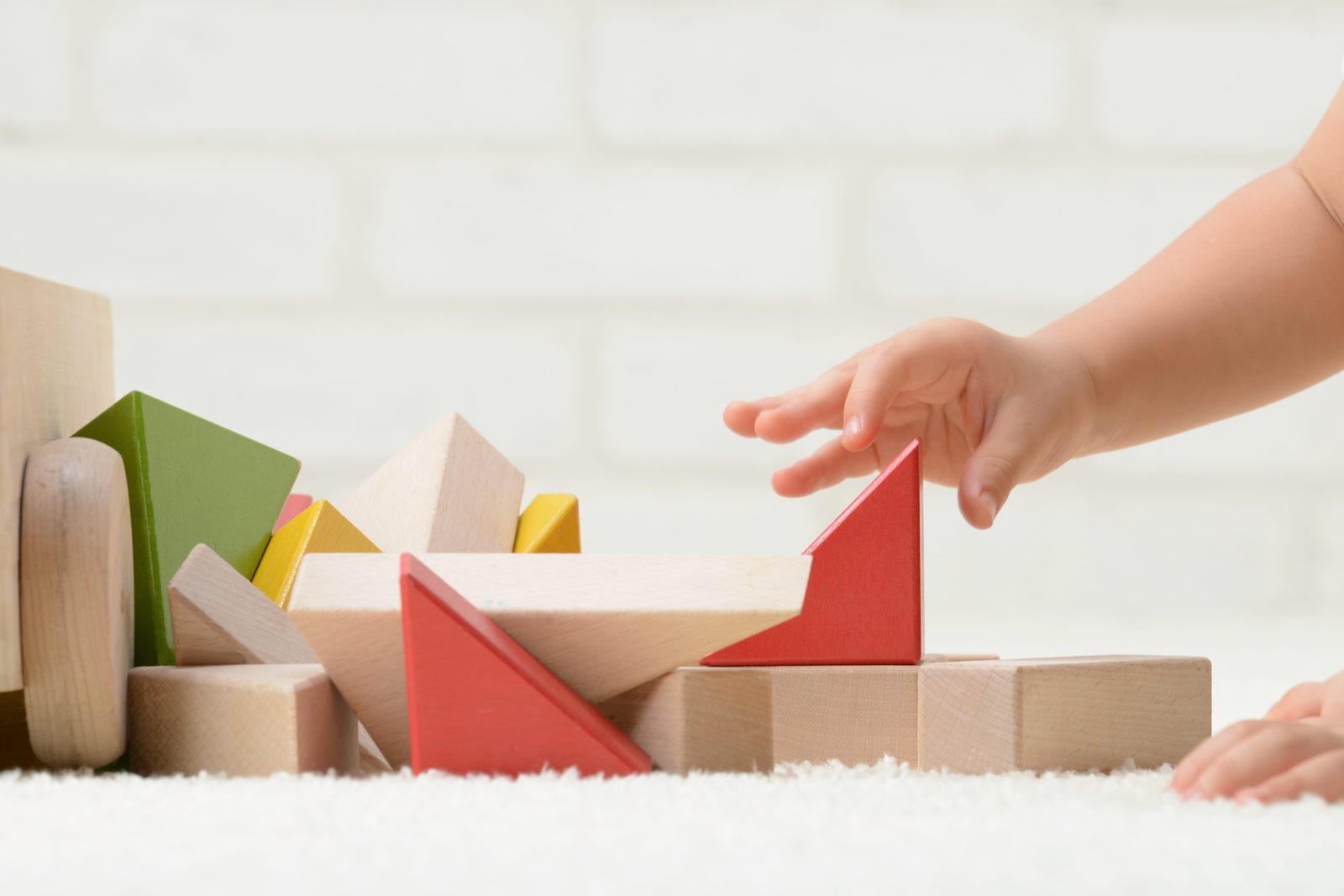 A child's hand playing with wooden blocks
